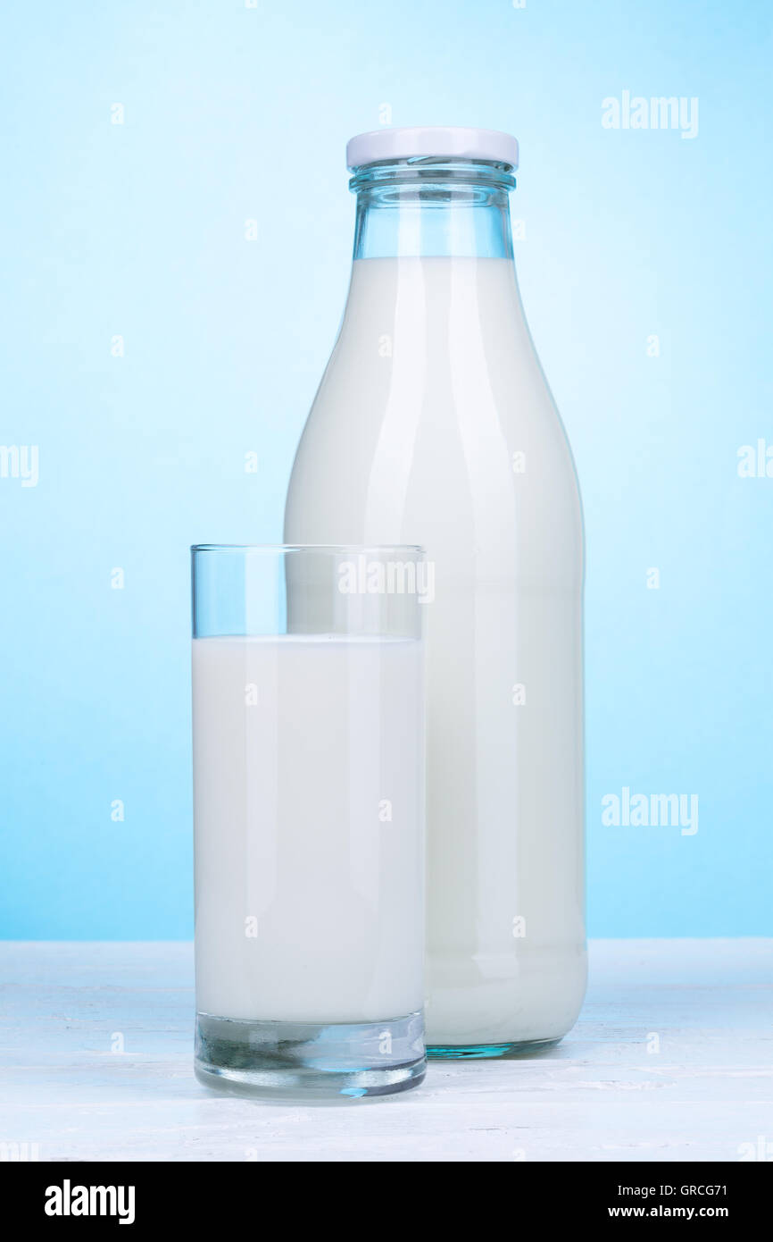 Bottle and glass of milk on white wooden board and light blue background Stock Photo