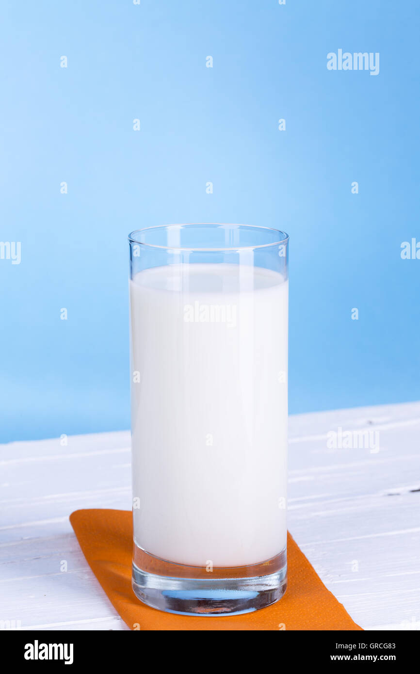 Glass of milk on white wooden board and light blue background Stock Photo