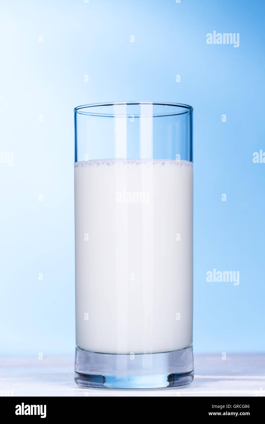 Glass of milk on white wooden board and light blue background Stock Photo