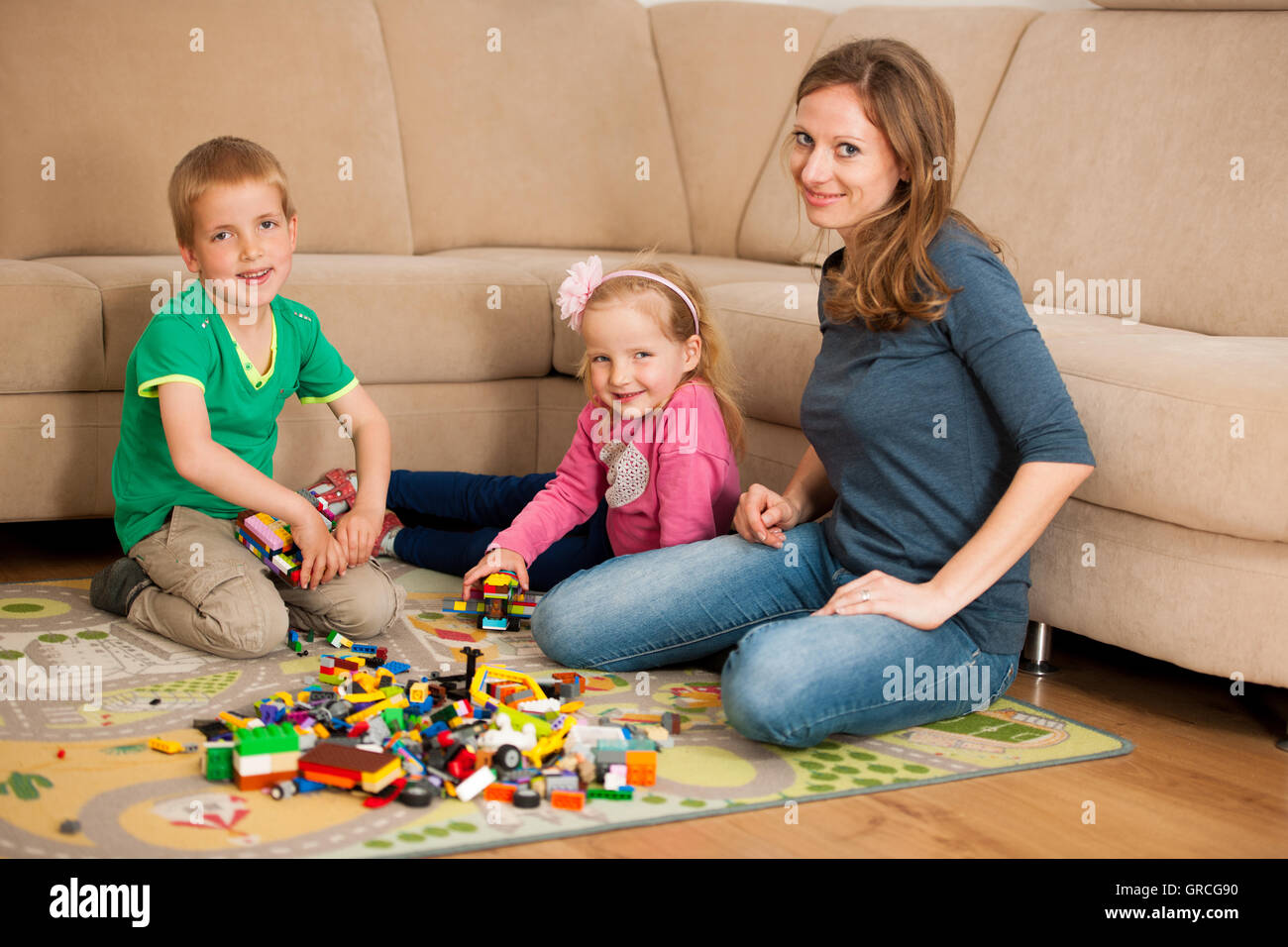 Children and their mother are playing with blocks on the ground in living room Stock Photo