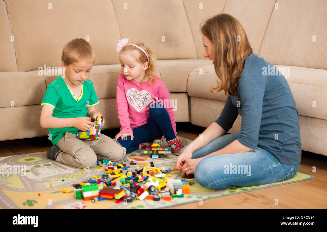 Mother son and daughter are playing with blocks on living room floors. Stock Photo