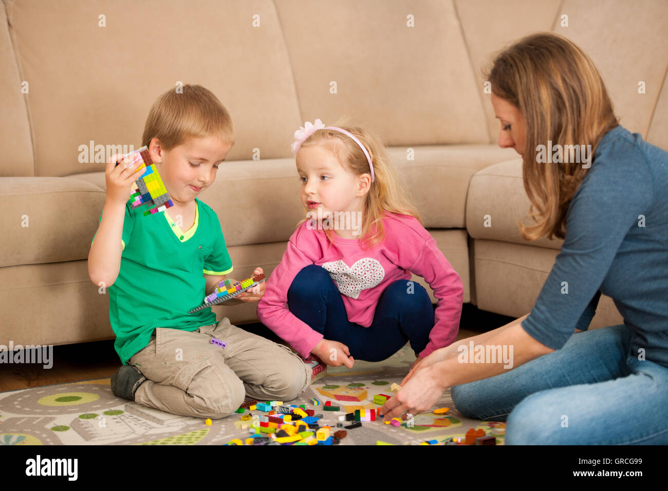 Mother son and daughter are playing with blocks on living room floors. Stock Photo
