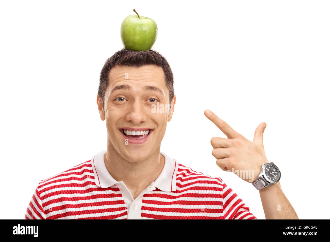 Happy guy pointing at an apple on his head isolated on white background