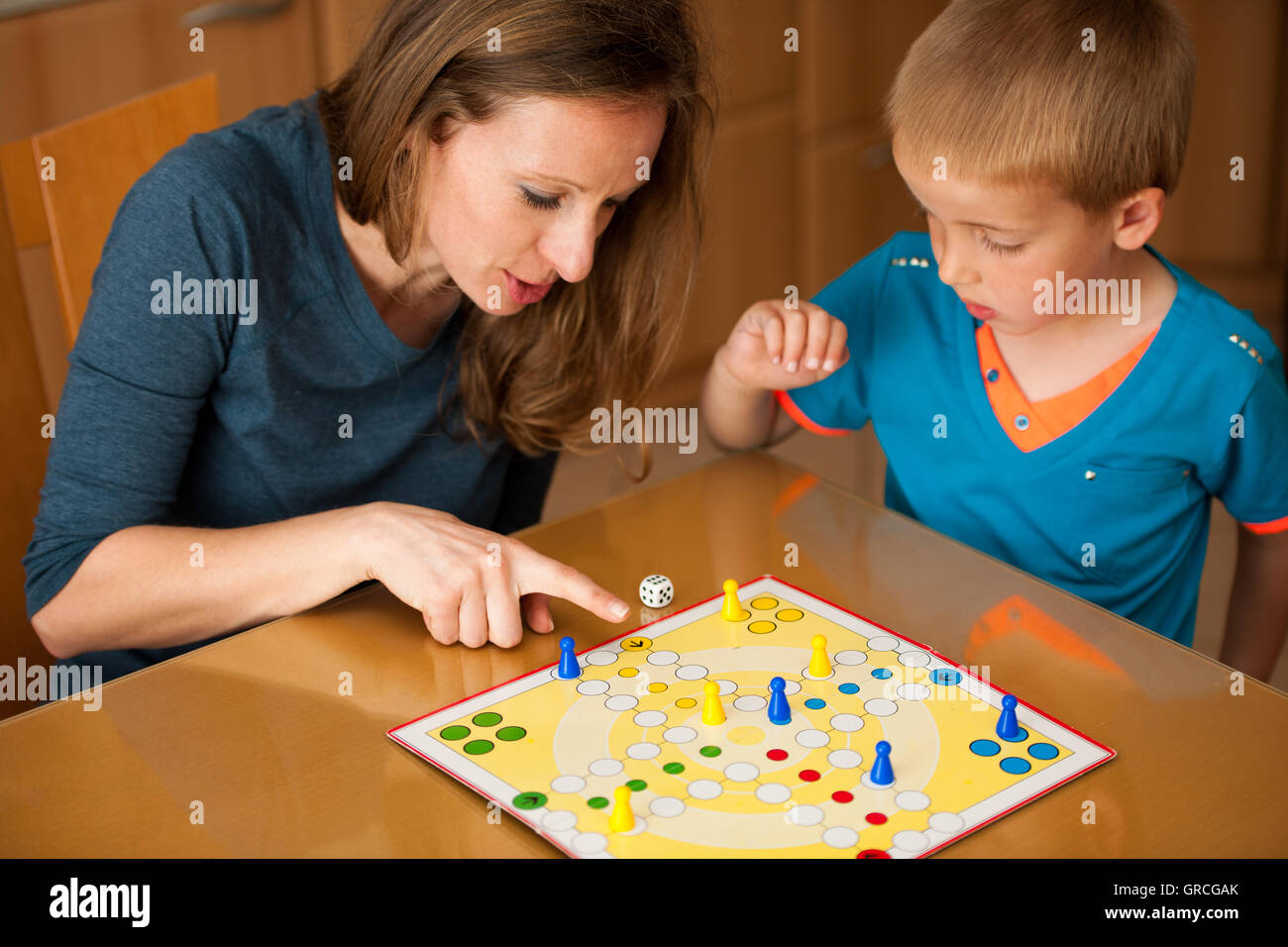 Mother and son playing ludo game at home. Stock Photo