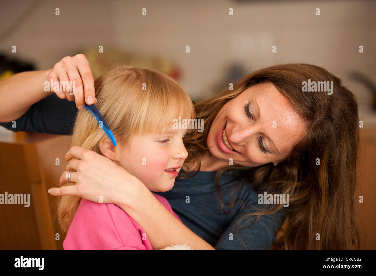 Mother combs hair to a cute little girl Stock Photo