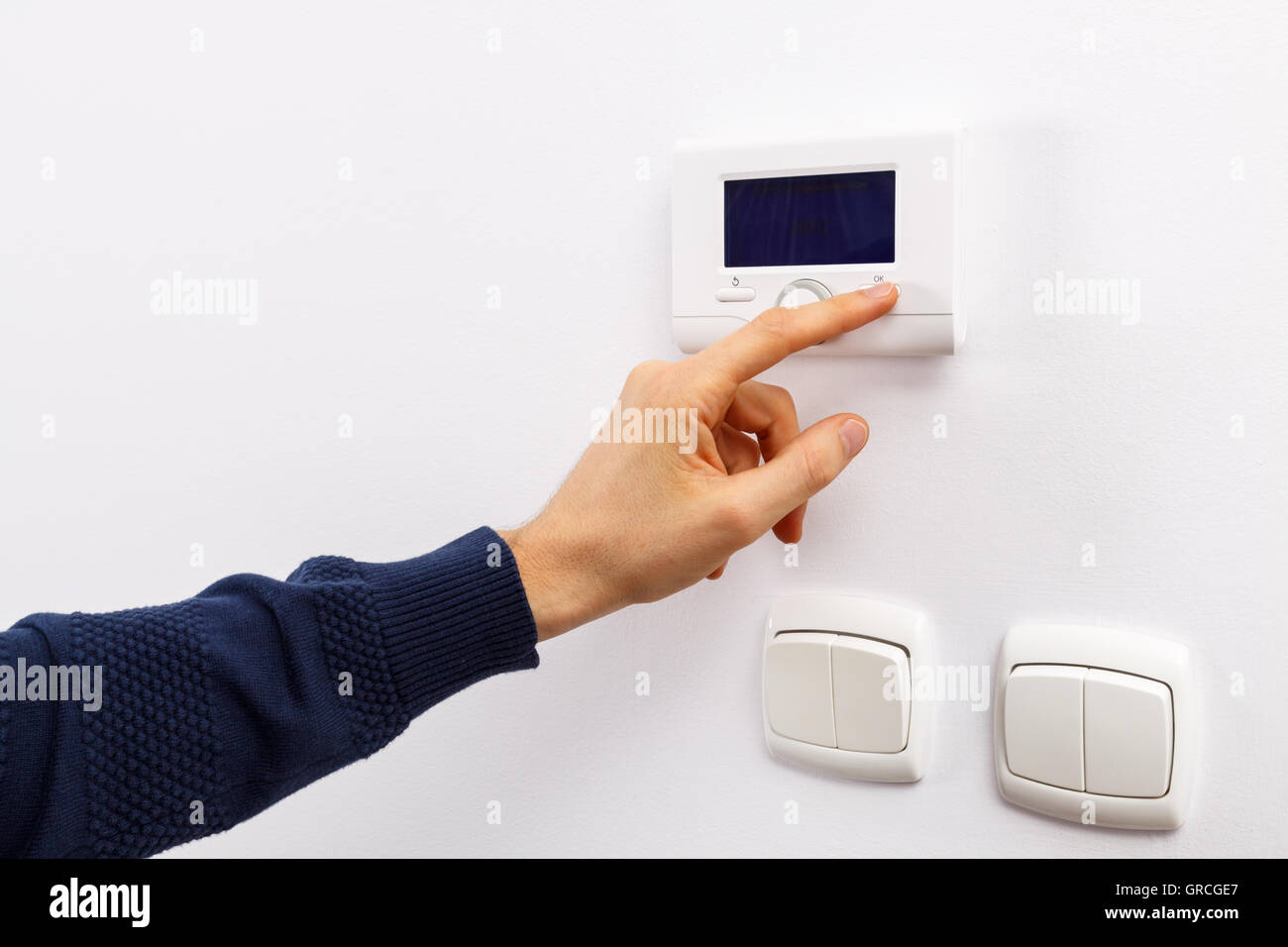 Men hand setting the temperature on control panel of DHW or central heating. Stock Photo