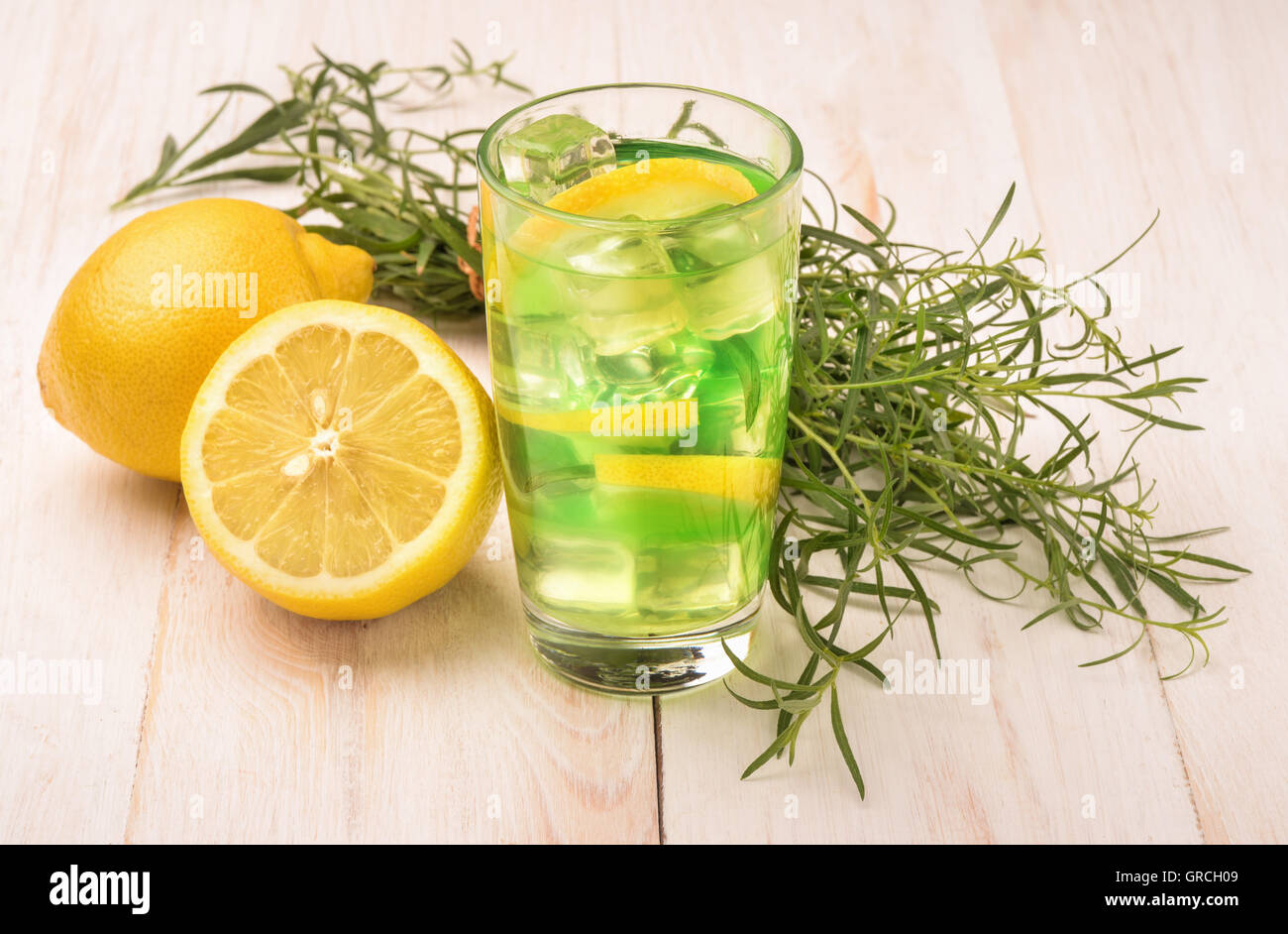 Glass of fresh homemade lemonade with tarragon and lemon on wooden table Stock Photo