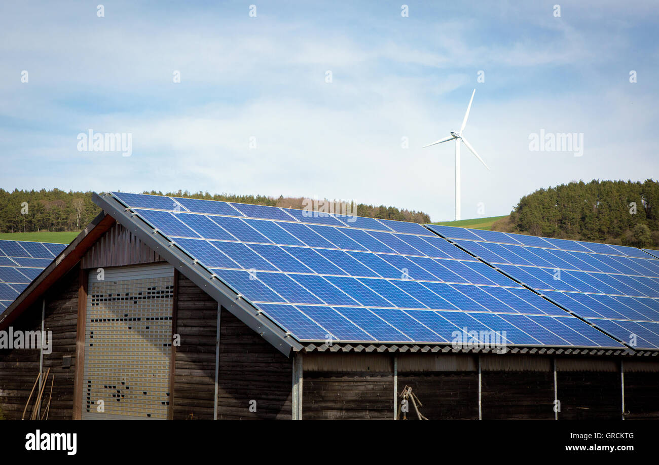 Agricultural Property With Photovoltaic System, In Background Wind Turbine Stock Photo
