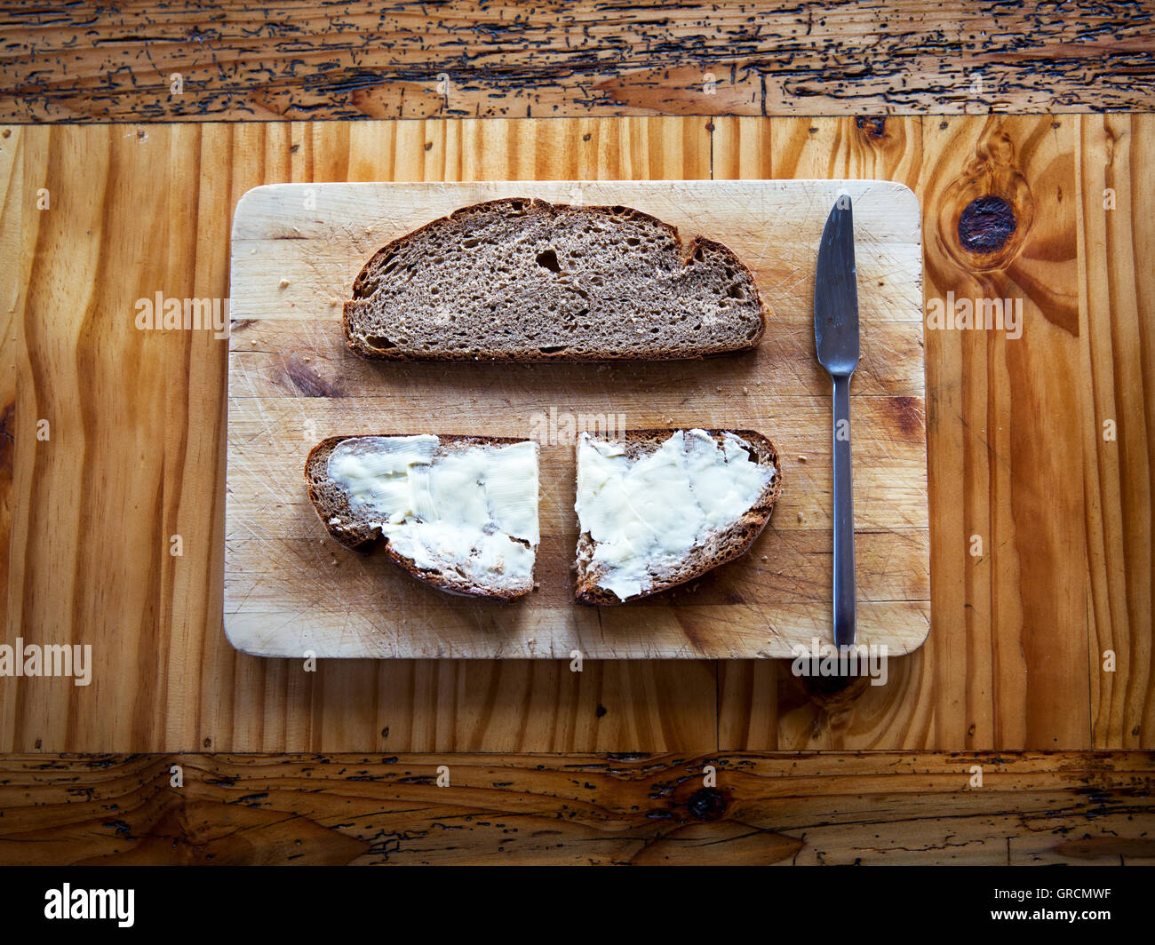Choppingboard With Butter And Bread On A Wooden Table Stock Photo