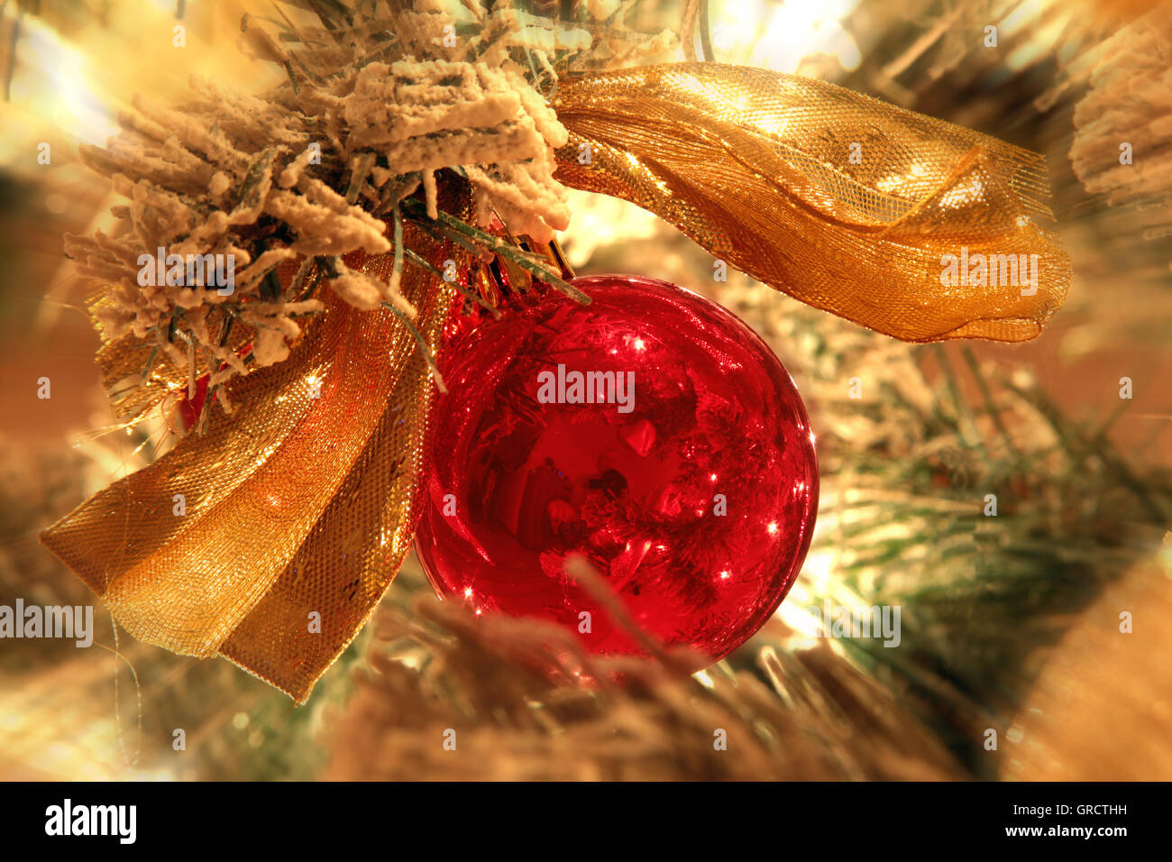 Red Christmas Tree Ornament With Golden Colored Bow In An Illuminated Tree Stock Photo