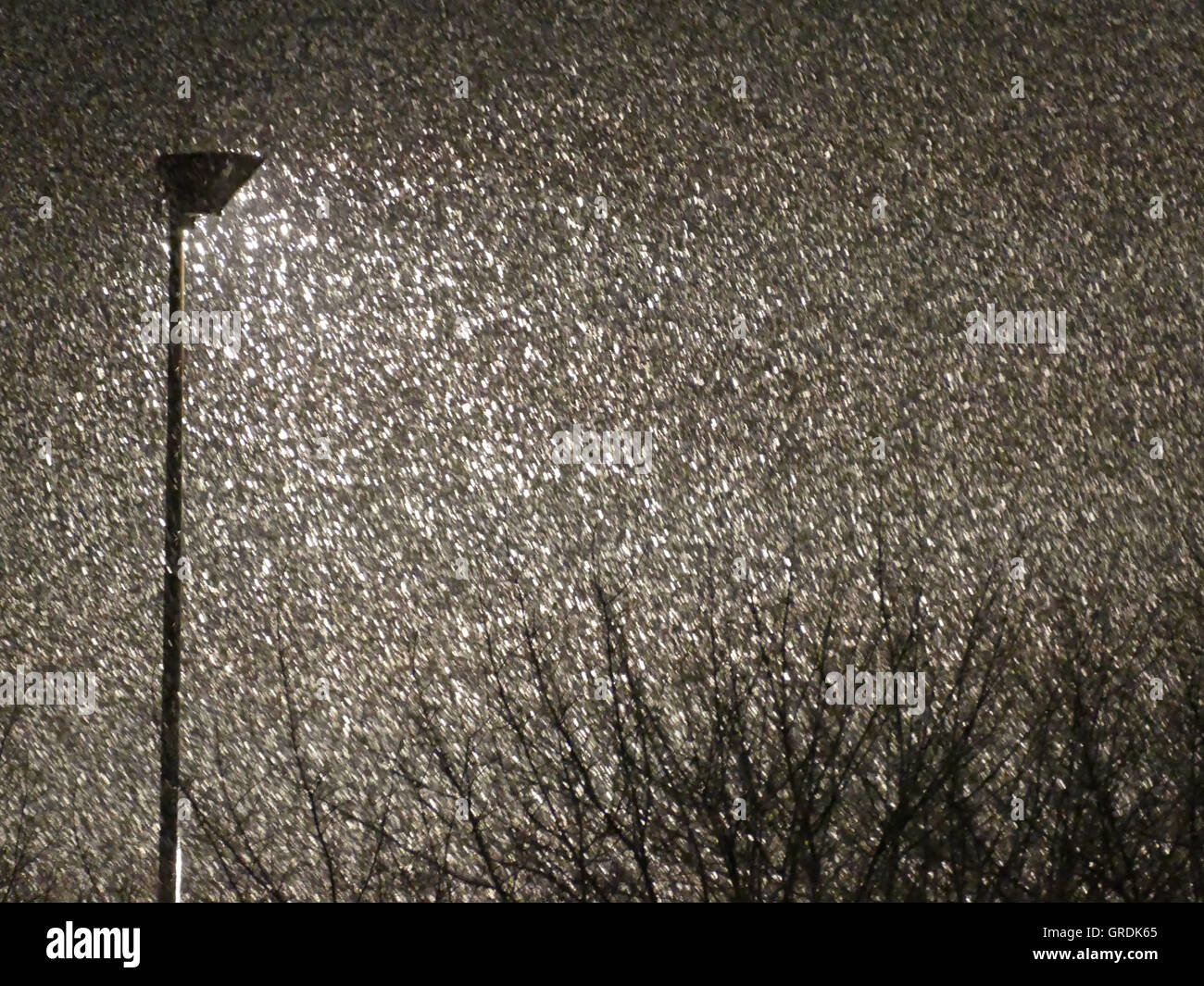 Snowflakes Dance In Front Of Floodlights At Night Stock Photo