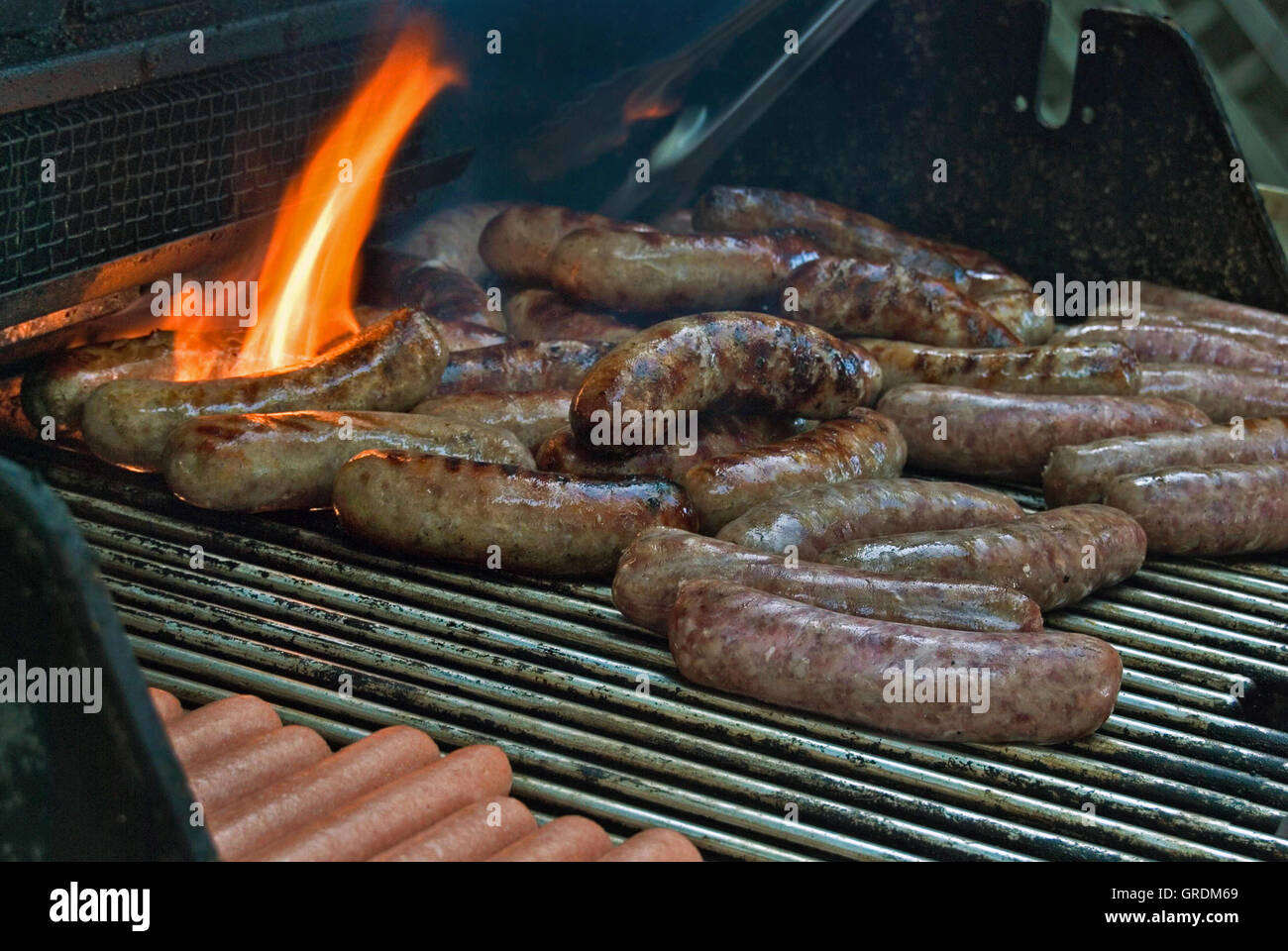 bratwurst and hot dogs on barbecue grill with flame Stock Photo