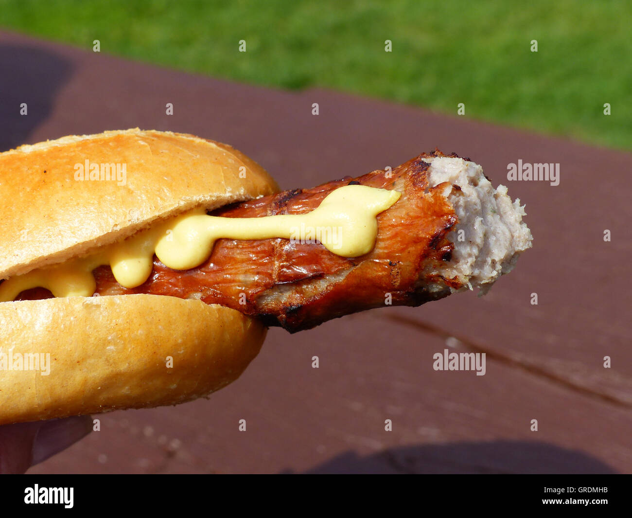 Bitten Into A Grilled Sausage With Mustard Stock Photo