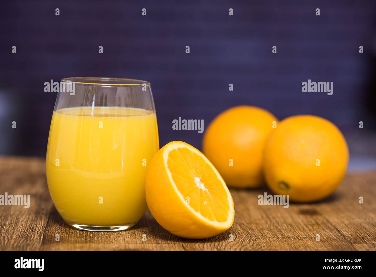 Glass of orange juice with half an orange leaning next to it Stock
