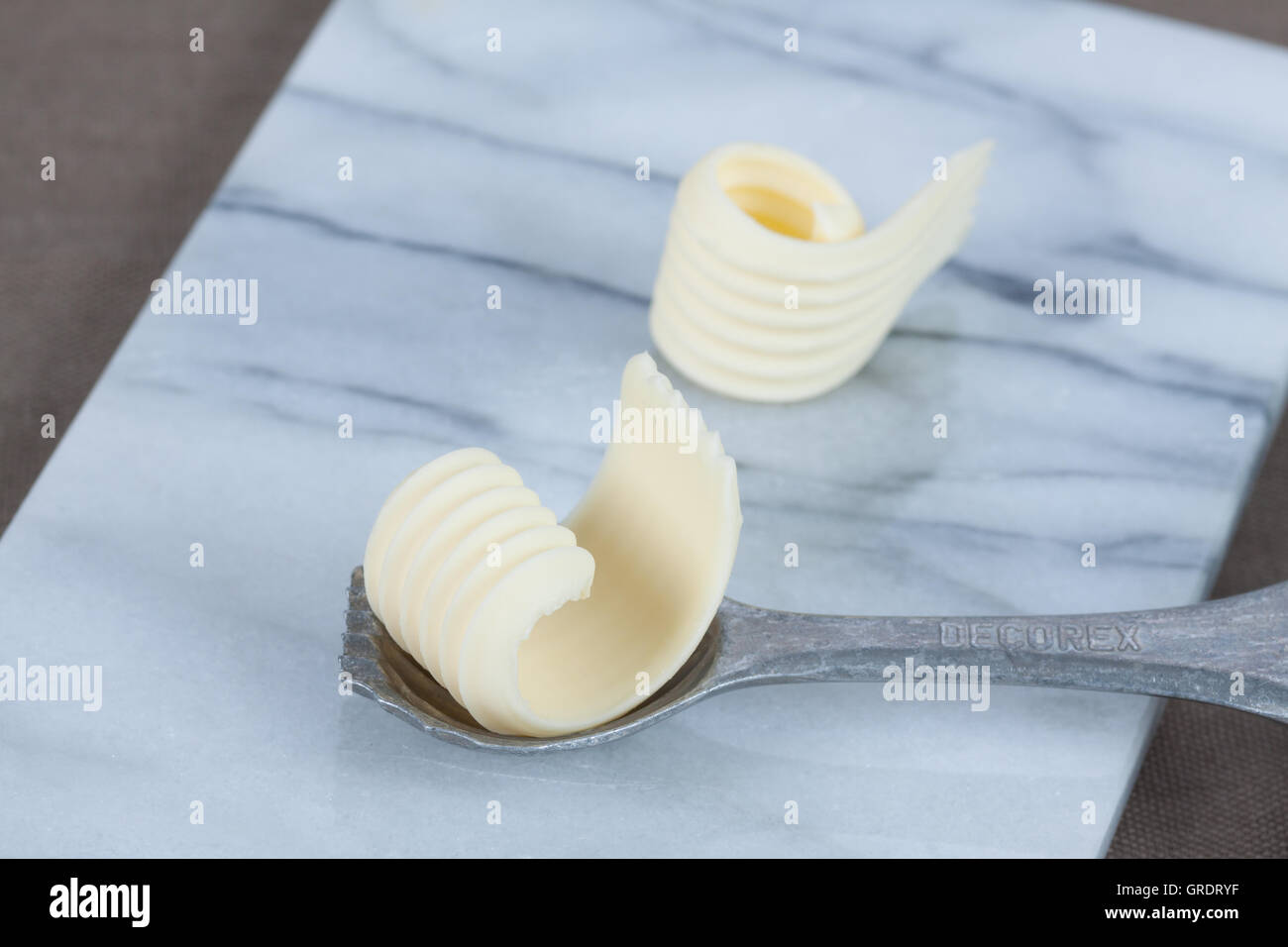Two Butter Curls On A Marble Slab With Decorative Spoon Stock Photo