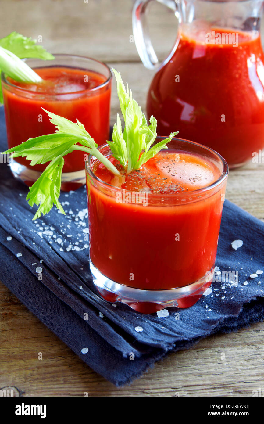 Tomato juice with celery, spices, salt and ice in portion glasses