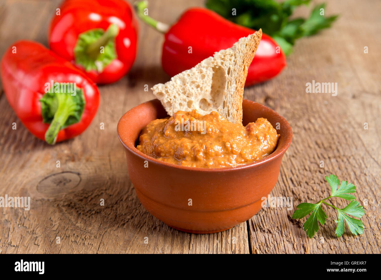 roasted pepper dip with nuts and bread in ceramic bowl over rustic