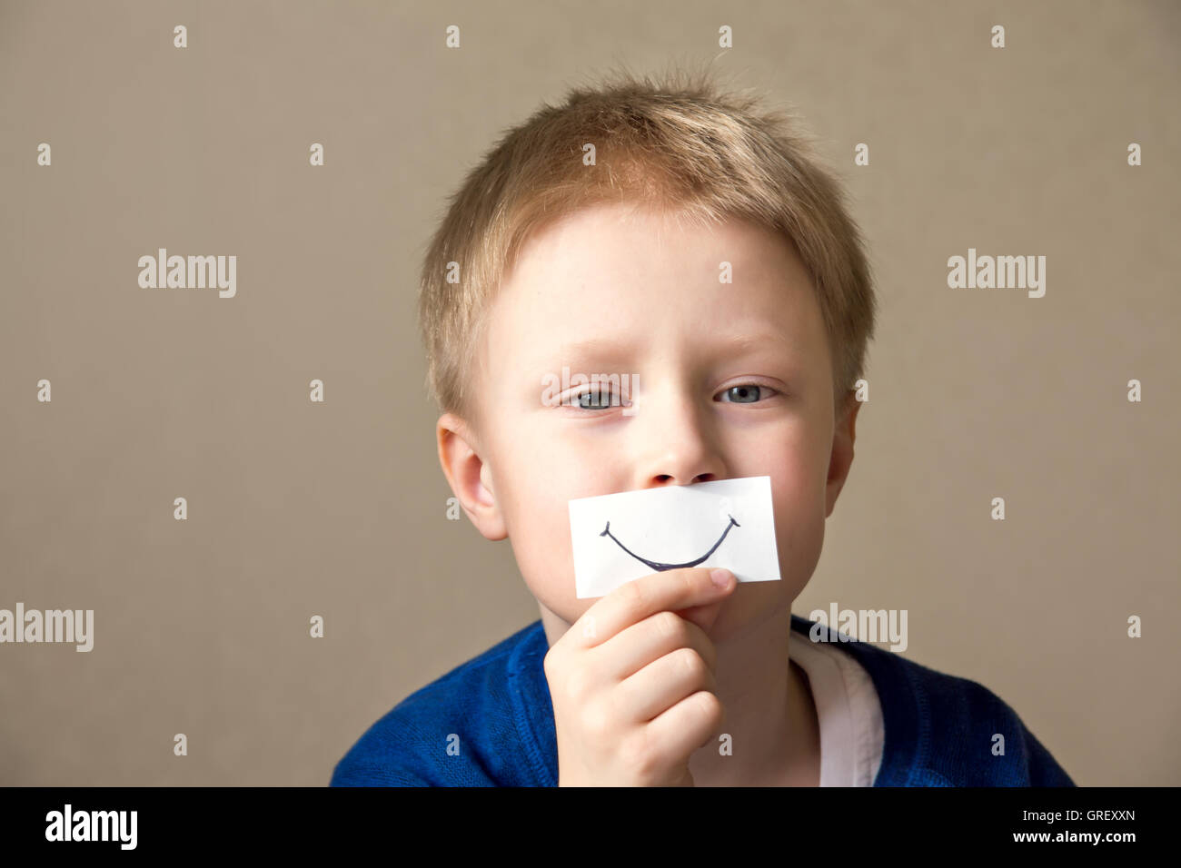Young boy with paper smile select right positive expressions (hides true feelings) Stock Photo