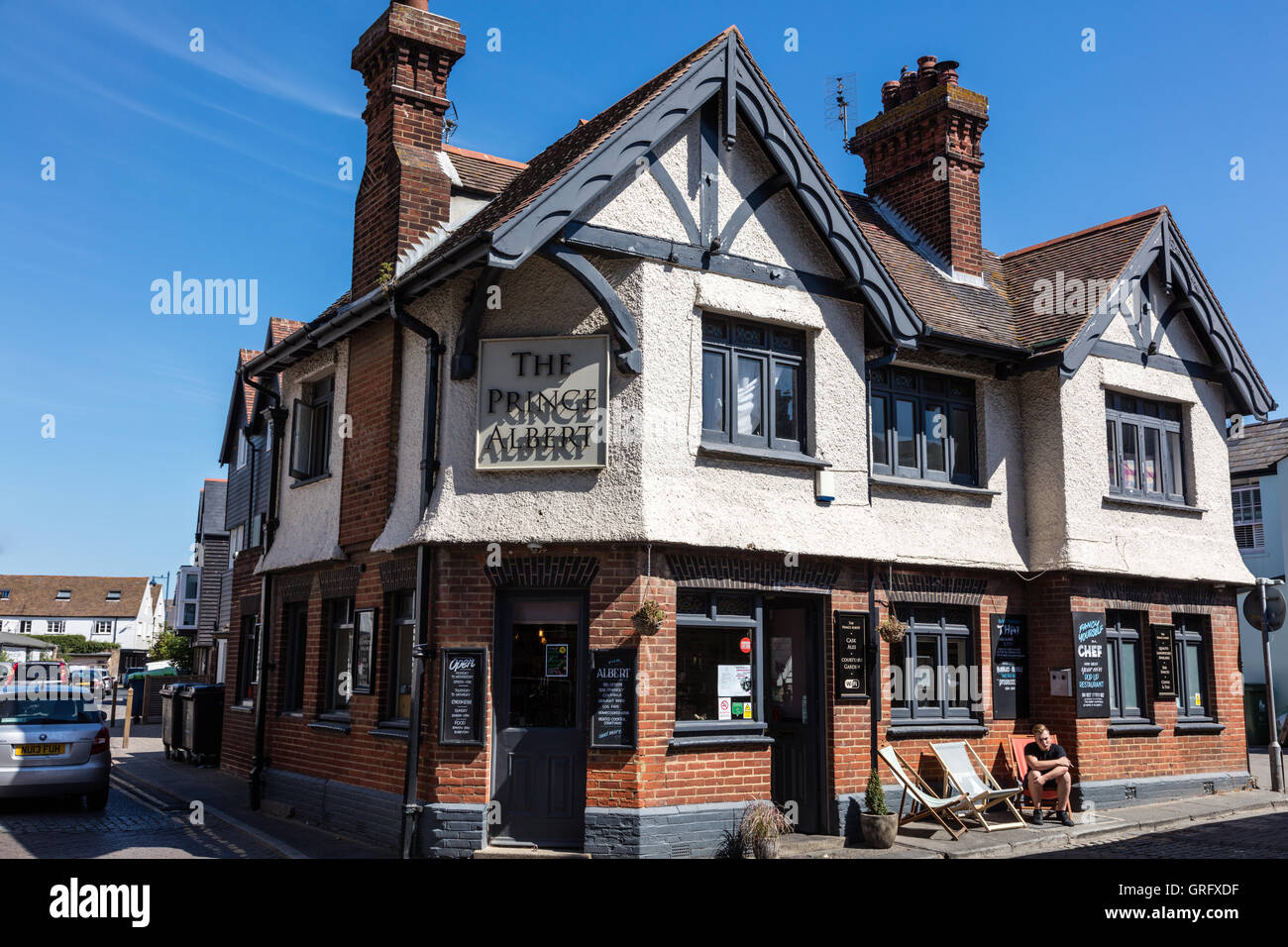 A man sits in a deckchair outside the Prince Albert a pub in Harbour Street, Whitstable, Kent, UK Stock Photo