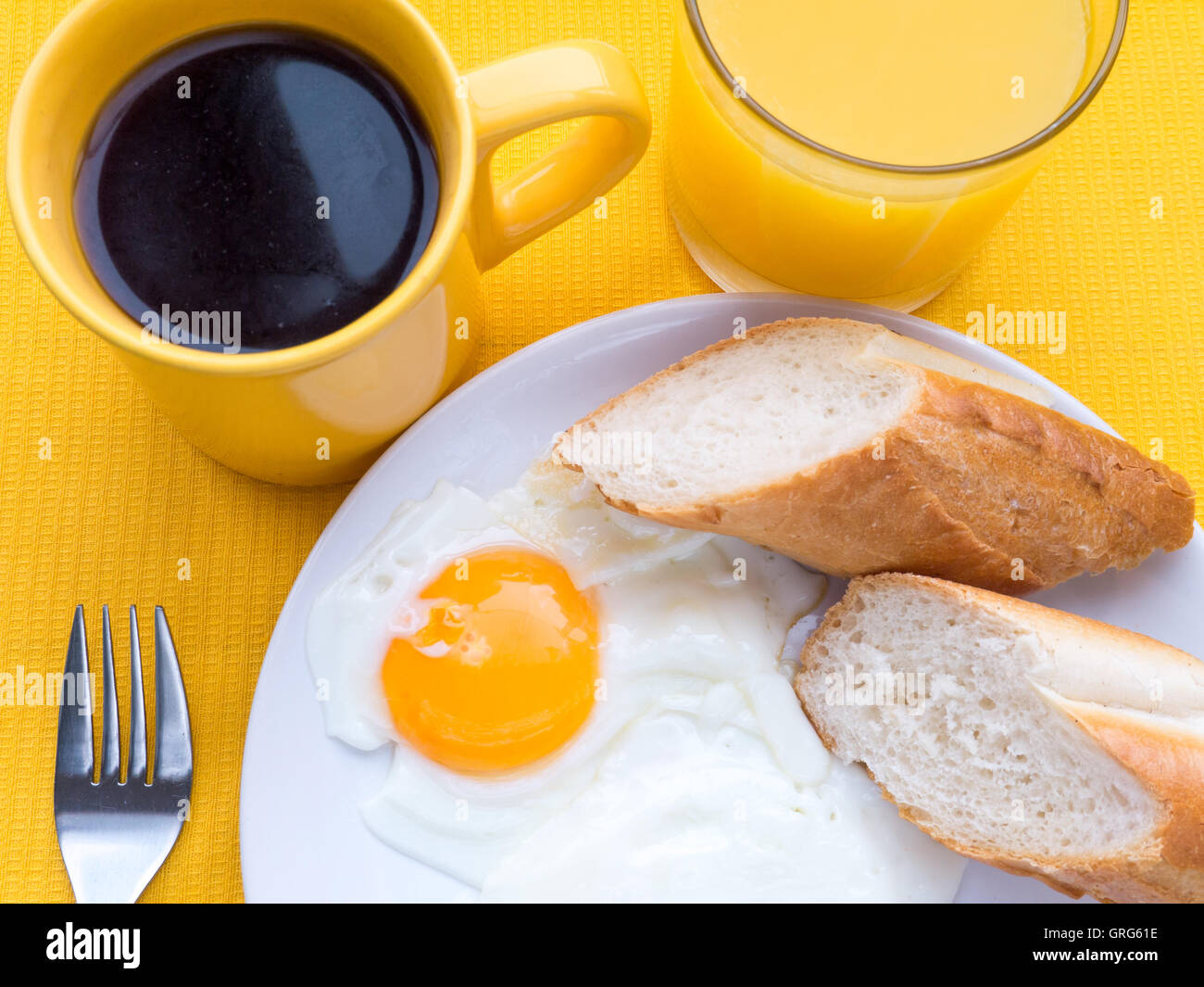Fried eggs, coffee and orange juice breakfast on the yellow tablecloth top view Stock Photo