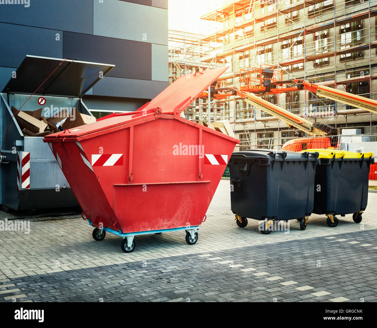 Red dumpster, recycle, waste and garbage bins near new office building