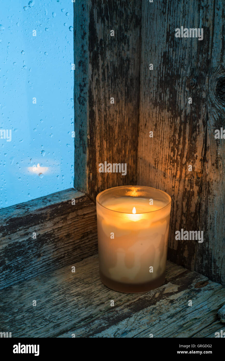 Burning candle on the sill of a window. Christmas ornament Stock Photo -  Alamy