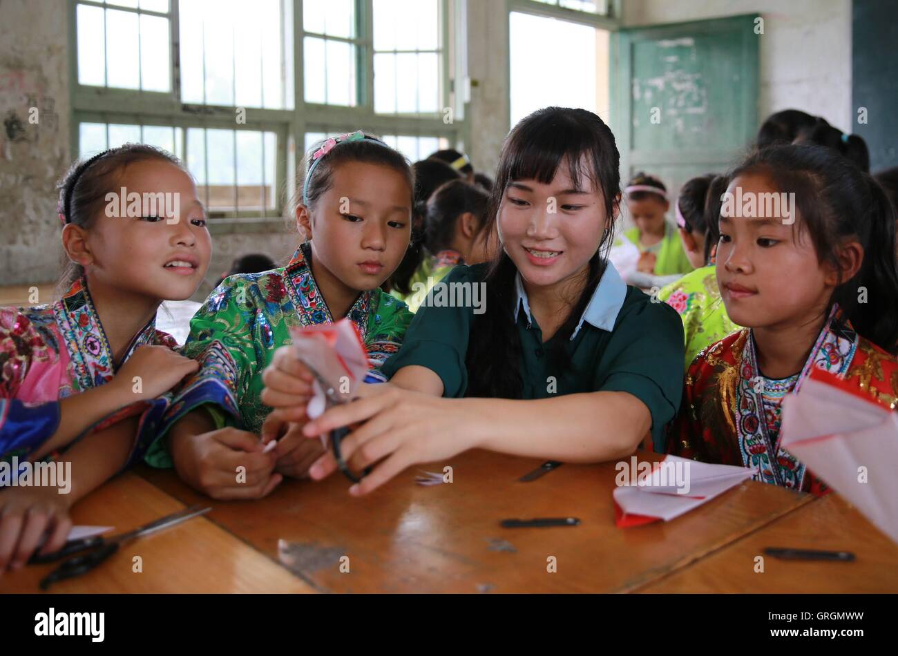 Liuzhou. 7th Sep, 2016. Wu Zhongyan (2nd R), a rural primary school teacher, teaches her students paper cutting in Gaoma Village Primary School, where most students are 'left-behind children', in Liuzhou, south China's Guangxi Zhuang Autonomous Region. The phrase is used in China to describe rural children whose parents work in other cities. Left-behind children usually live with relatives, often their grandparents, while their parents work away from home. © Long Tao/Xinhua/Alamy Live News Stock Photo