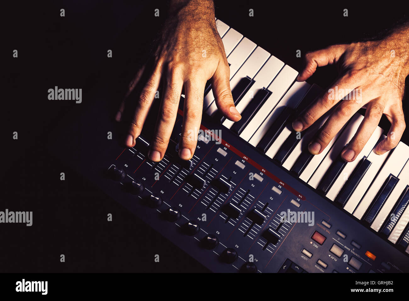 Details of a modern midi keyboard with male hands playing on it Stock