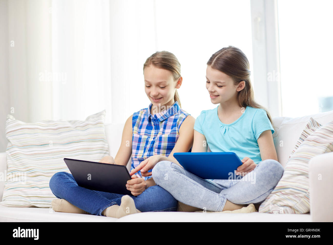 happy girls with tablet pc sitting on sofa at home Stock Photo - Alamy