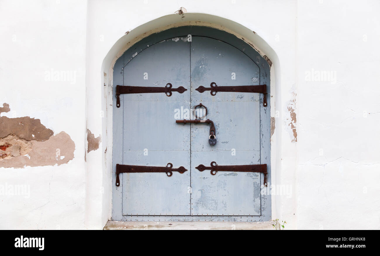 Locked gray wooden door with arch in old red white stone wall, background photo texture Stock Photo