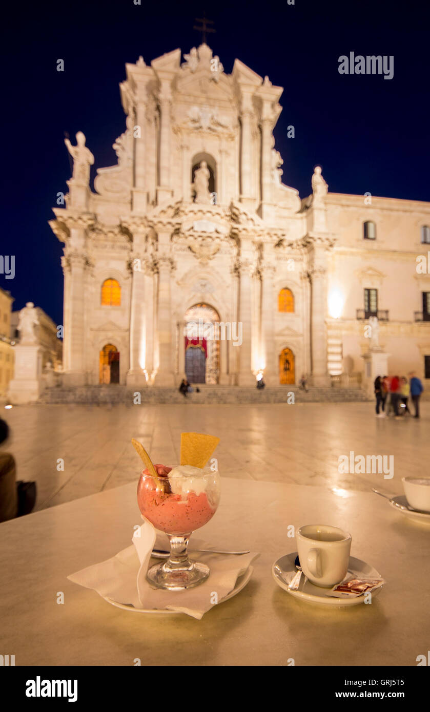 Gelato Italian ice cream and cup of espresso on table in evening night with cathedral across square Piazza del Duomo Siracusa Stock Photo