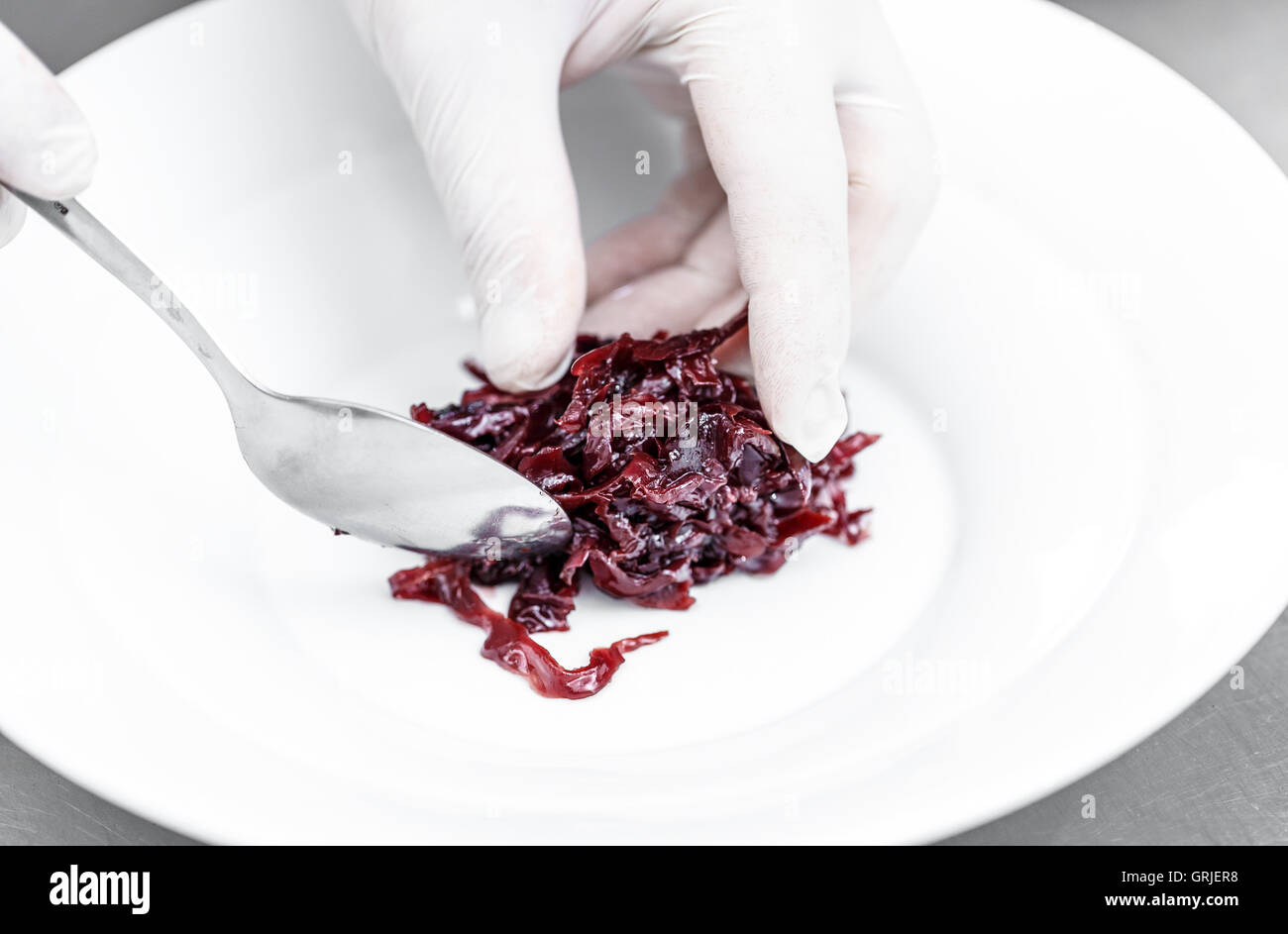 Chef serving spicy red cabbage on white plate Stock Photo
