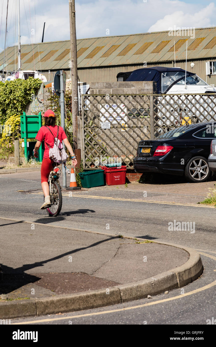 A  girl on a monocycle dressed in red, Brightlingsea, Essex Stock Photo