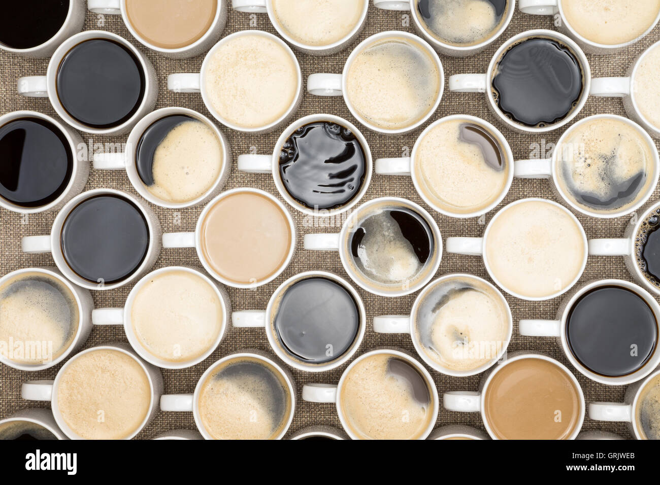 Conceptual image of regimented rows of coffee mugs lined up in straight rows with their handles facing the same direction like c Stock Photo