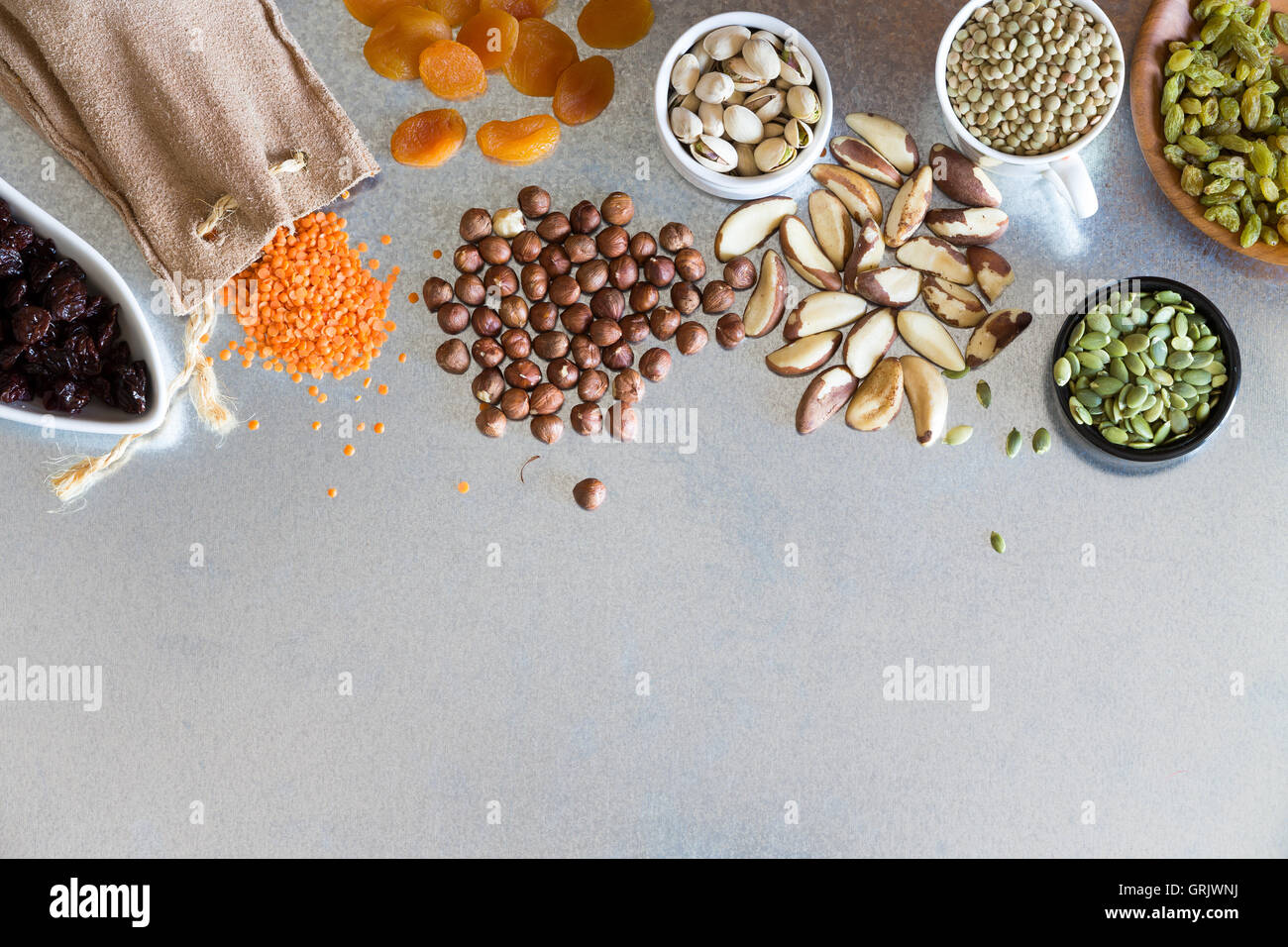 Variety dried raisins, hazel and macadamia nuts and grains displayed on a metal surface for a