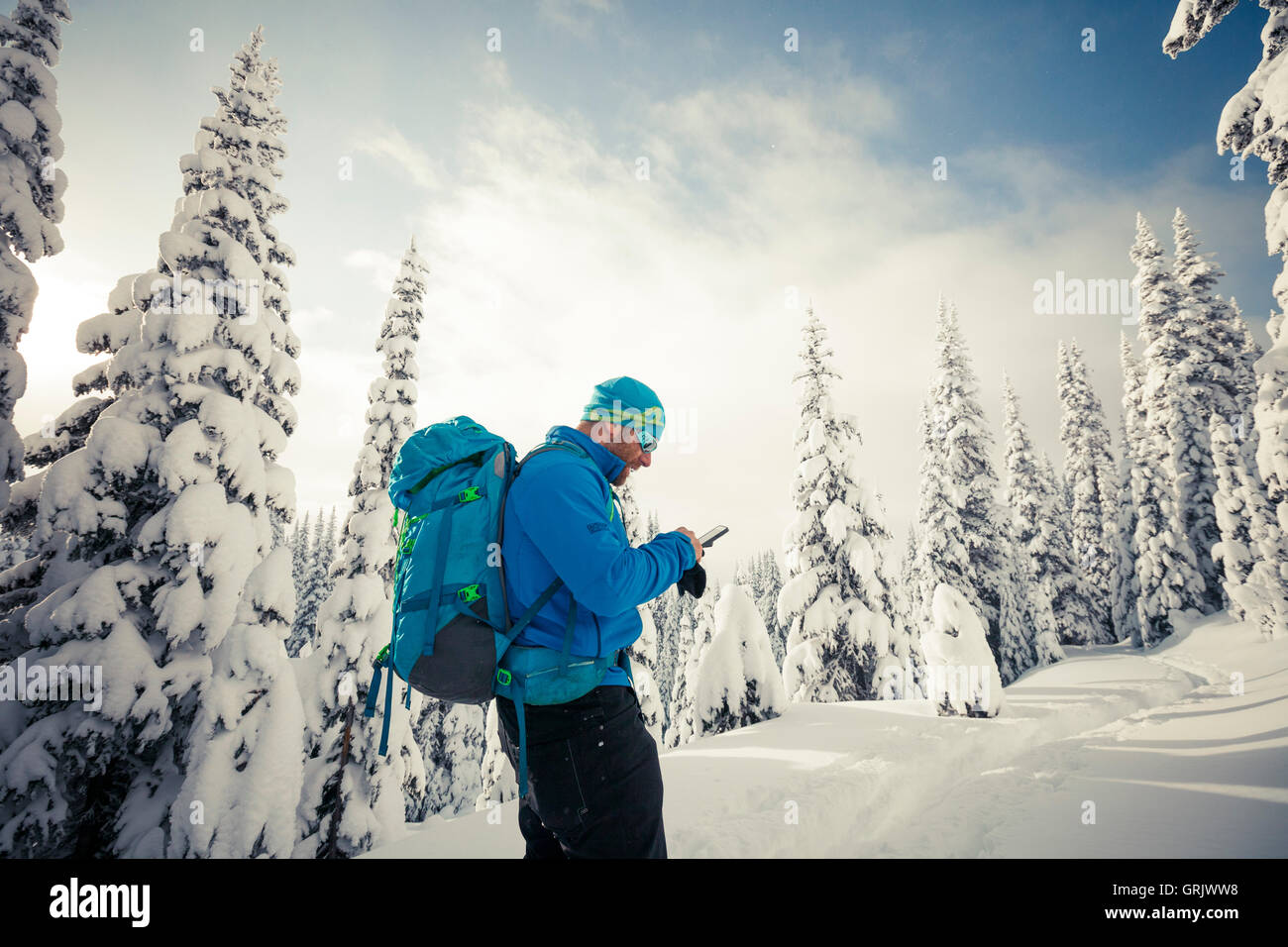 A skier stops to check his smartphone during a backcountry ski trip. Stock Photo