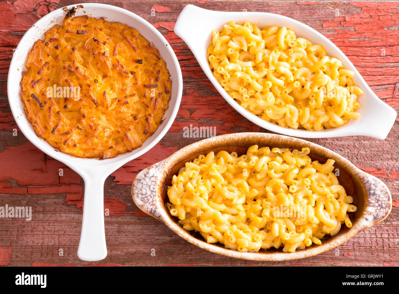 Three cheese macaroni in different clay pots on rustic table served hot Stock Photo