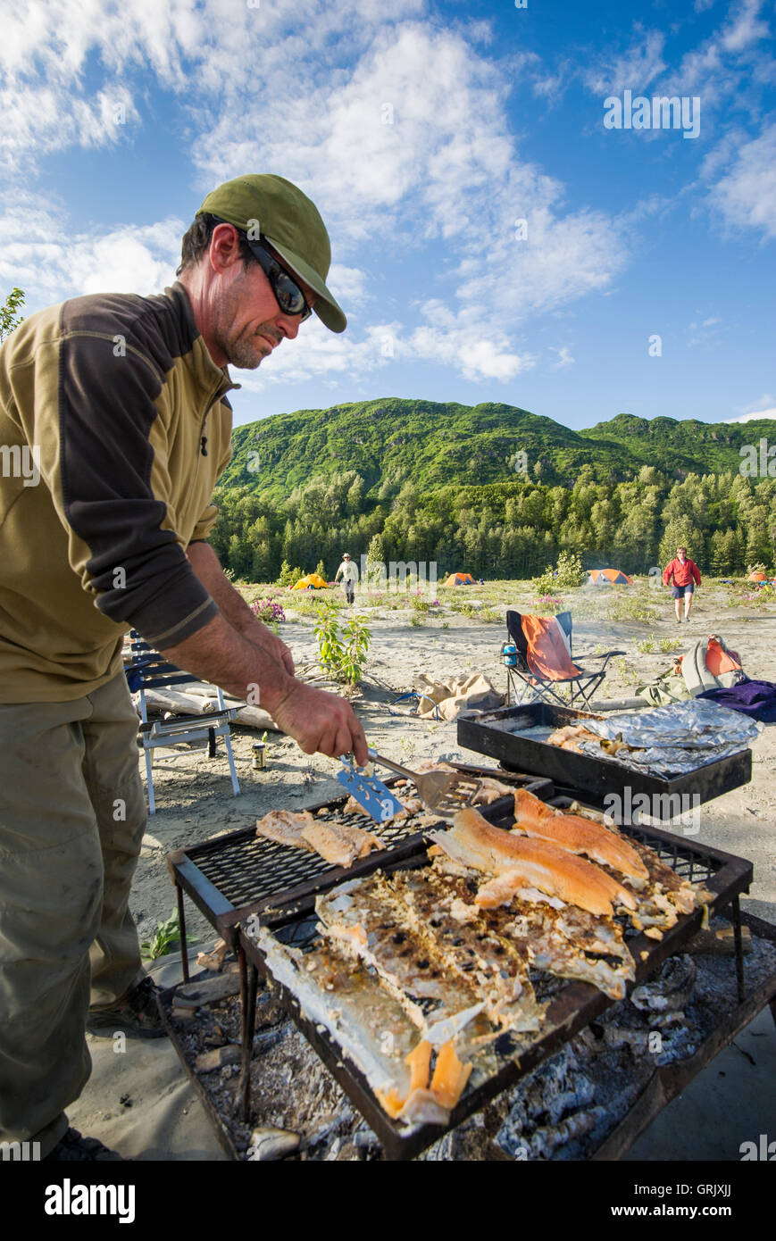 Rafter cooking fish over open fire on the shores of the Alsek River Stock Photo