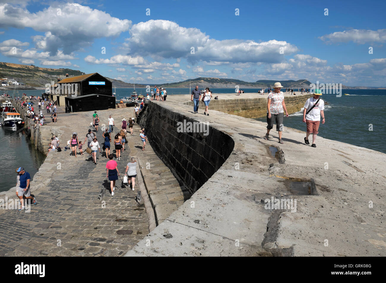 People walking on the Cobb on a sunny summer day at Lyme Regis, Dorset, England UK  KATHY DEWITT Stock Photo