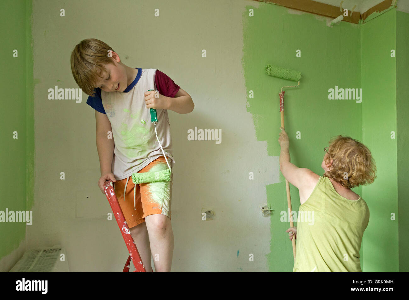 young boy painting himself while his mother is renovating the flat Stock Photo