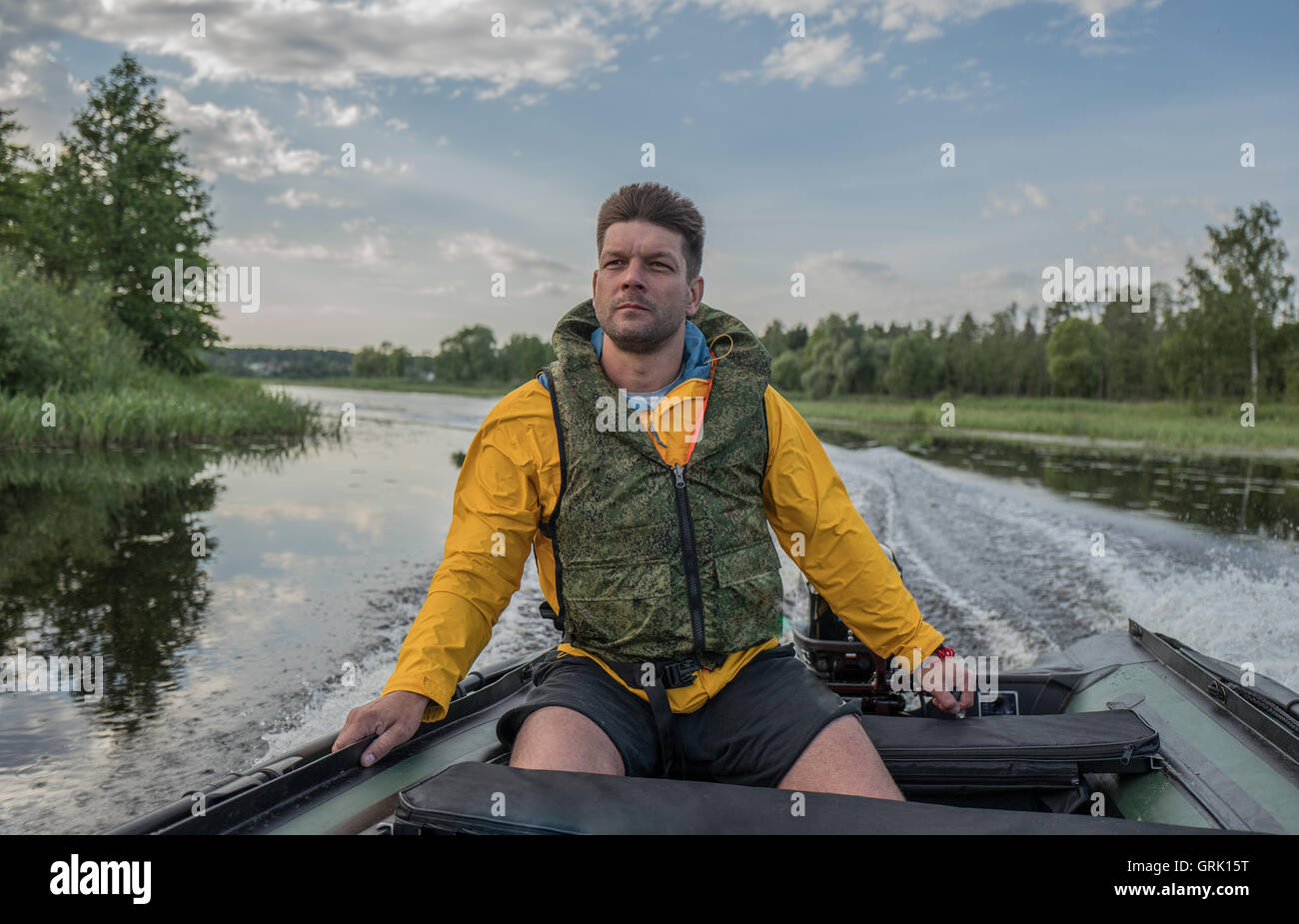 Brave handsome man is operating of boat on the river Stock Photo