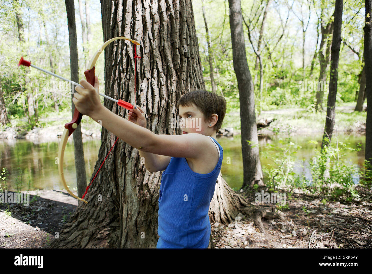 10 year old girl playing with toy bow and arrow beside a creek in Minneapolis, Minnesota. Stock Photo