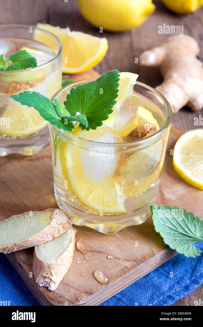 Ginger ale soda with lemon, mint, ginger and ice over rustic wooden