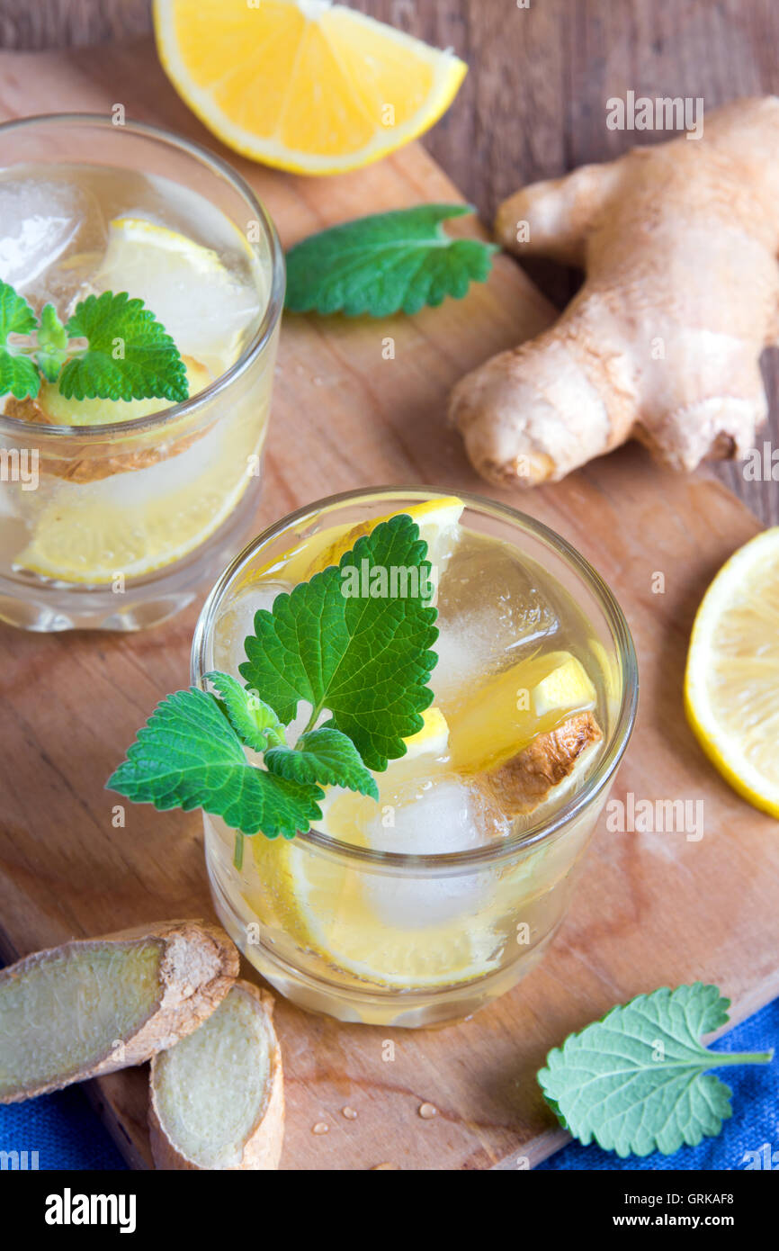 Ginger ale soda with lemon, mint, ginger and ice over rustic wooden