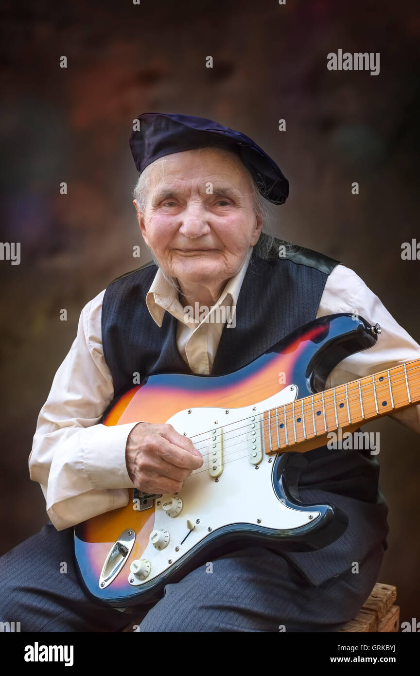 Elderly woman playing guitar. Selective focus. Stock Photo