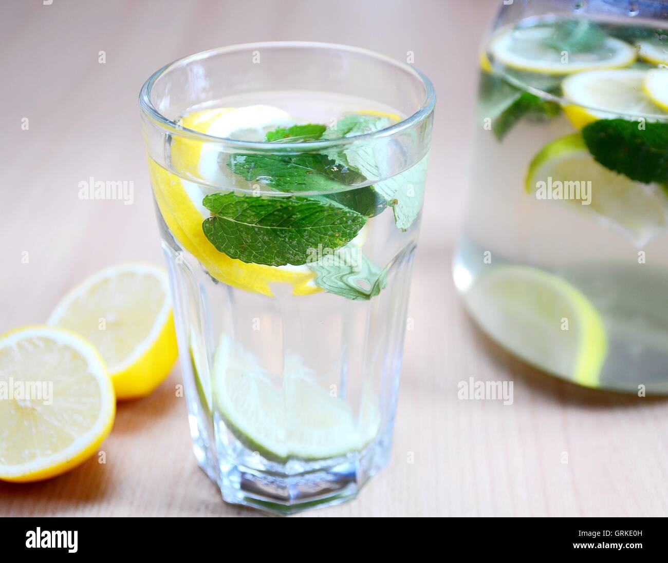 Fresh non-alcoholic drink with water, mint leaves, peaces of lemons and limes in glass. Stock Photo