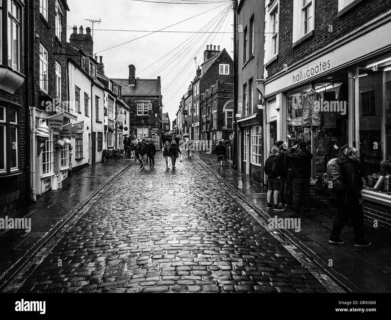 Various people on Church Street, in the rain. In Whitby, North