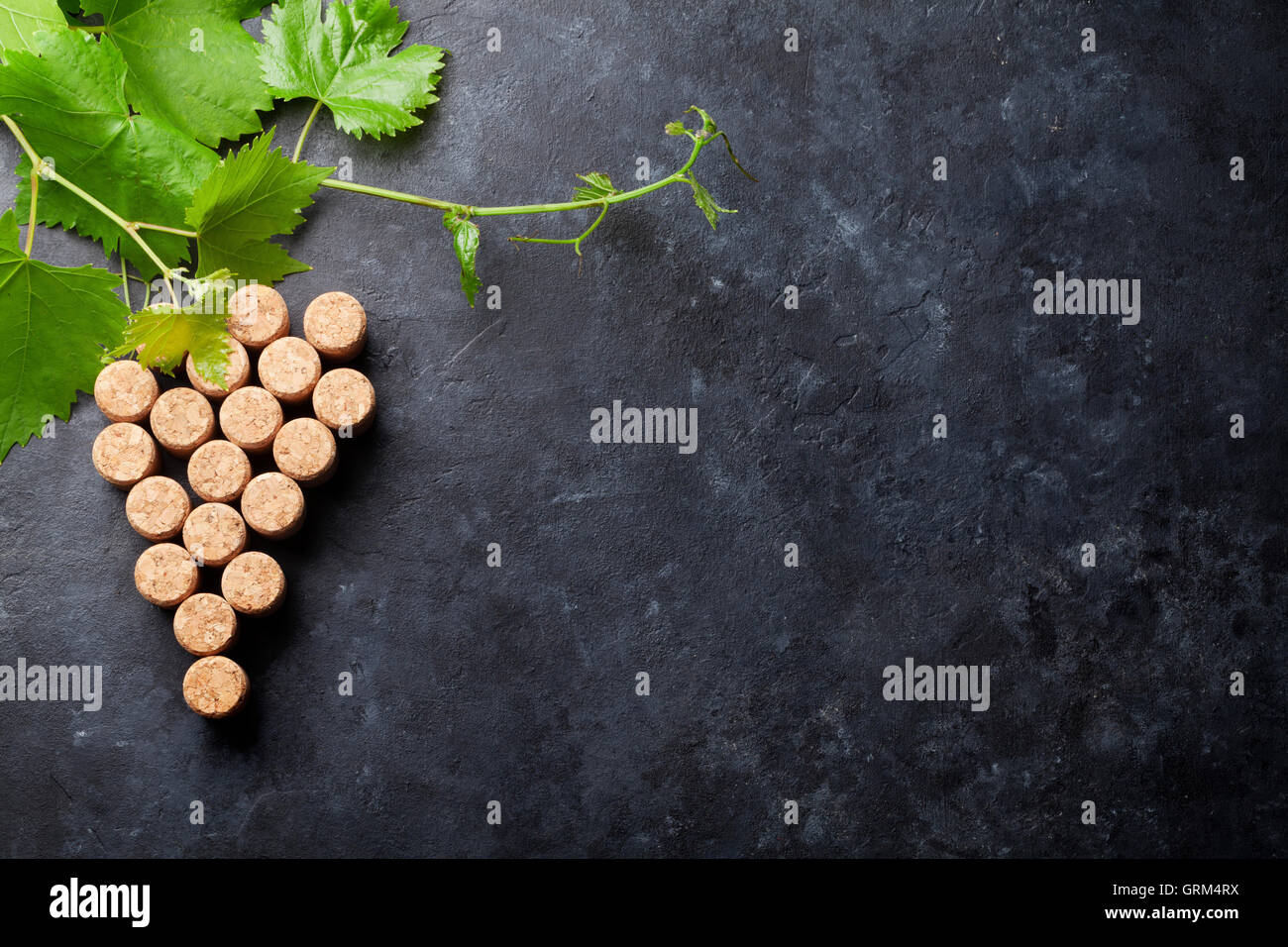 Wine corks grape shape and vine on stone table. Top view with copy