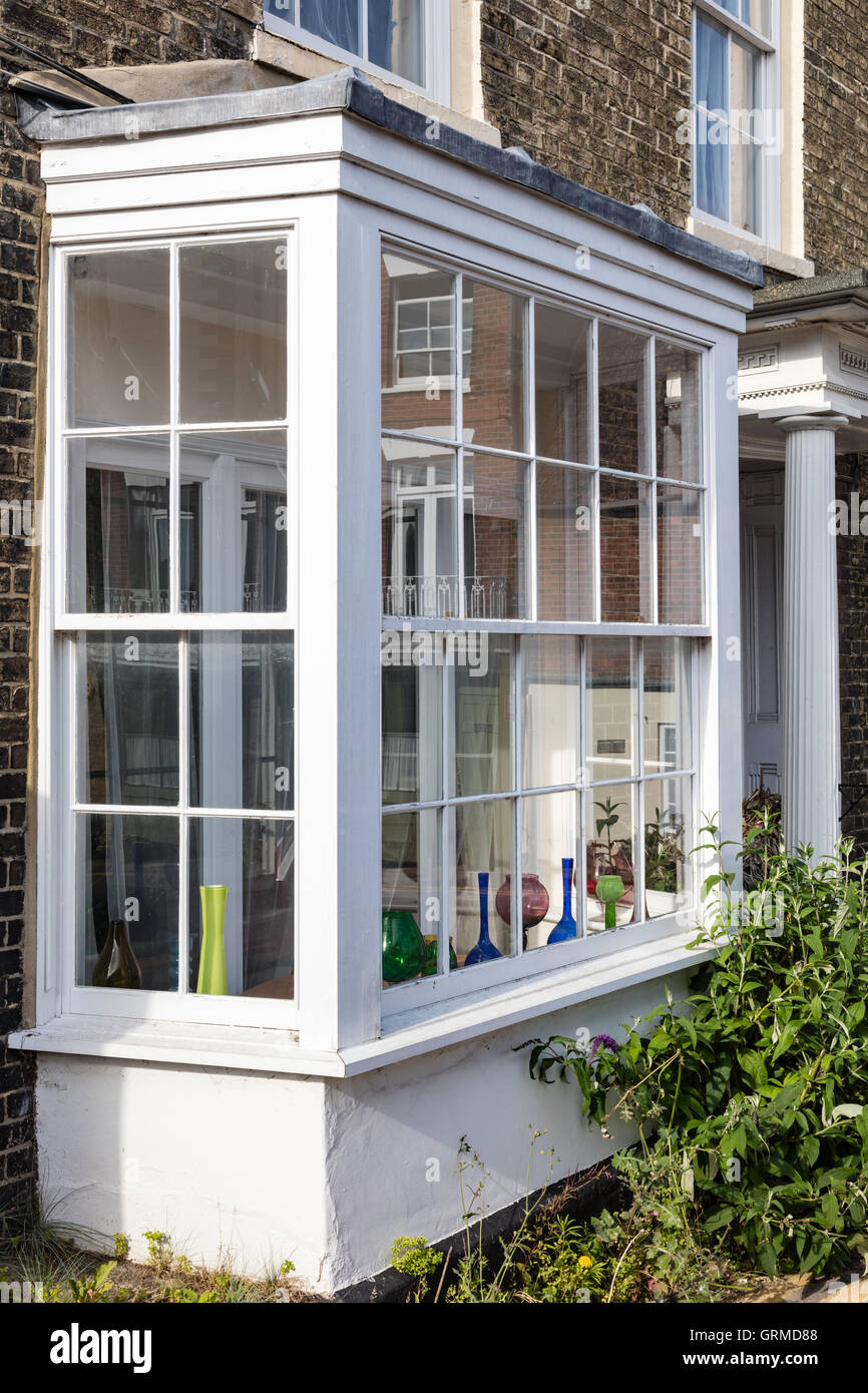 A coloured glass display of vases on the bay windowsill of an