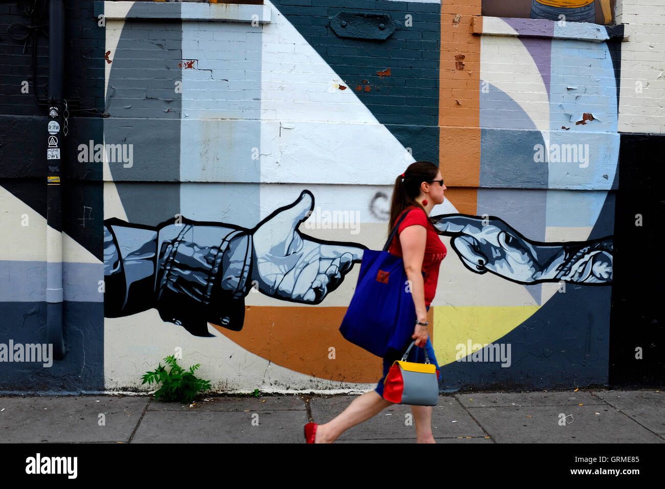 A woman walking pass by a mural along Christopher Columbus Drive in Historic Downtown,Jersey City,New Jersey,USA Stock Photo